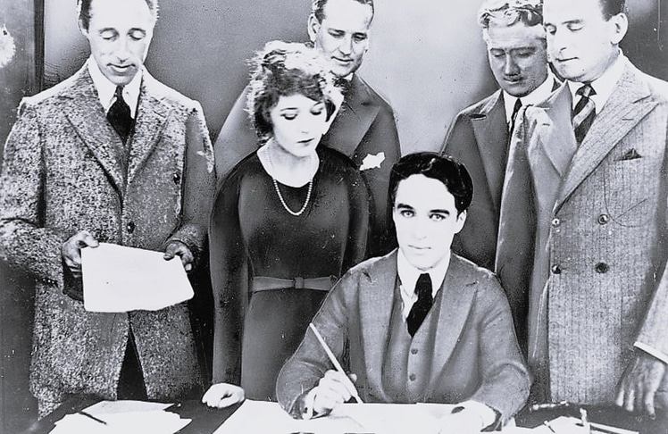 Fotomontage zur Unterzeichnung des Gründungsvertrags von United Artists inklusive des sitzenden Charlie Chaplin (Bild: US Library of Congress / gemeinfrei)