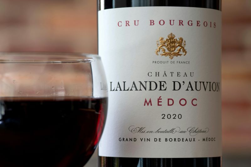 Prestige im Glas: Auch erschwingliche Bordeaux-Weine wie dieser Médoc setzen auf elegante Etiketten und Château-Tradition – ein Image, das weltweit zieht. © Brett Jordan/Unsplash