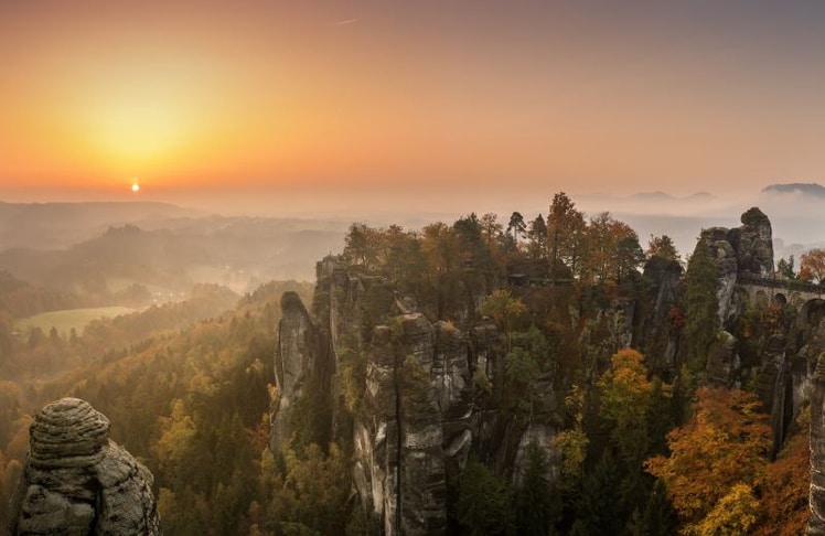 Goldener Oktober in Deutschland: Die Sächsische Schweiz zeigt sich mit leuchtenden Herbstwäldern, markanten Sandsteinfelsen und Sonnenaufgang über dem Elbtal von ihrer schönsten Seite. Die Region zählt zu fünf Reisezielen, die im Herbst besonders reizvoll sind. 