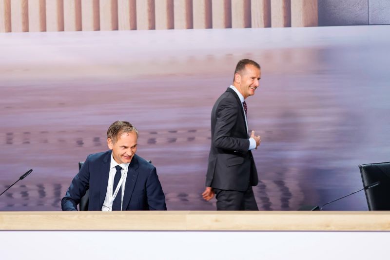 Volkswagen-CEO Oliver Blume (r.) und sein Vorgänger Herbert Diess bei einer Konzernveranstaltung. Während Blumes Vergütung nach dem Gewinneinbruch sinkt, zählt Diess weiterhin zu den bestbezahlten Managern des Unternehmens. © Volkswagen AG