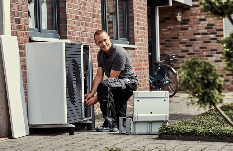 Symbolbild eines Installateurs bei der Montage einer Wärmepumpe