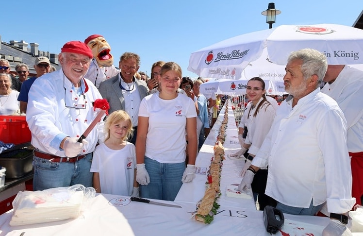 Mit Unterstützung seiner Enkeltöchter Linda und Annika schnitt Jürgen Gosch am Samstag, 08. August 2026 das unumstrittene Weltrekord-Fischbrötchen an